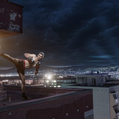 Young man boxing training on top of the house above the city